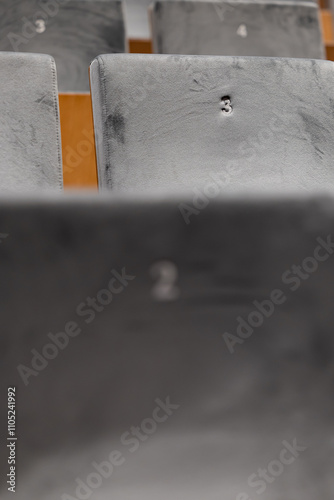 Rows of empty seats in a cinema hall,  front side of the seats with numbers. Close-up with shallow depth of field