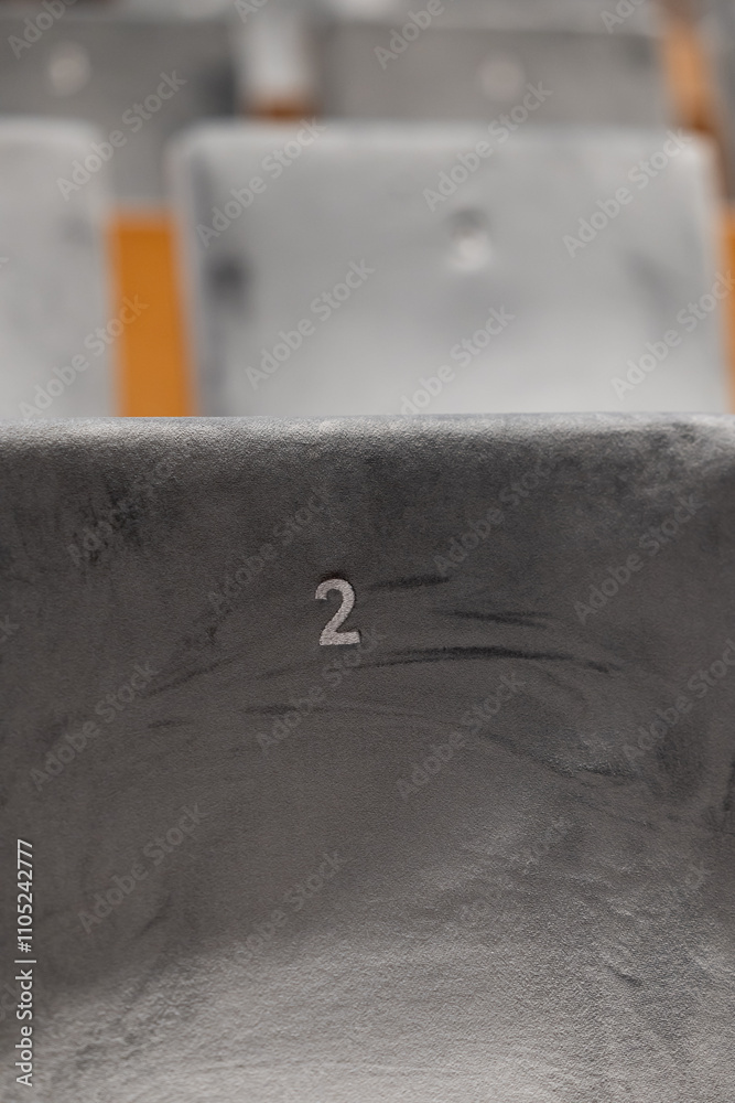 Rows of empty seats in a cinema hall, front side of the seats with numbers. Close-up with shallow depth of field