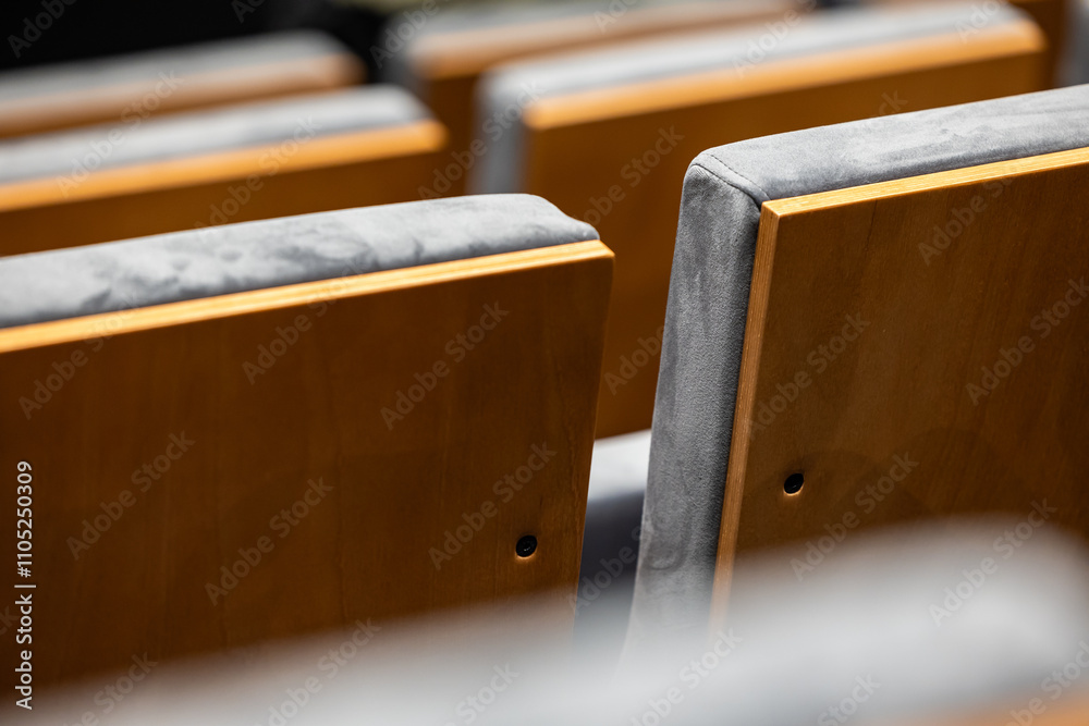 Rows of empty seats in a cinema hall - close-up with shallow depth of field. View of the back part made of light plywood.
