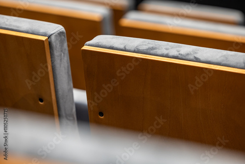 Rows of empty seats in a cinema hall - close-up with shallow depth of field. View of the back part made of light plywood.