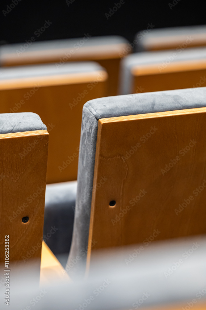 Rows of empty seats in a cinema hall - close-up with shallow depth of field. View of the back part made of light plywood.