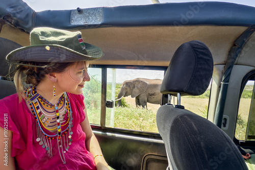 Canvas Print A Caucasian girl in a hat looks at animals in the savannah
