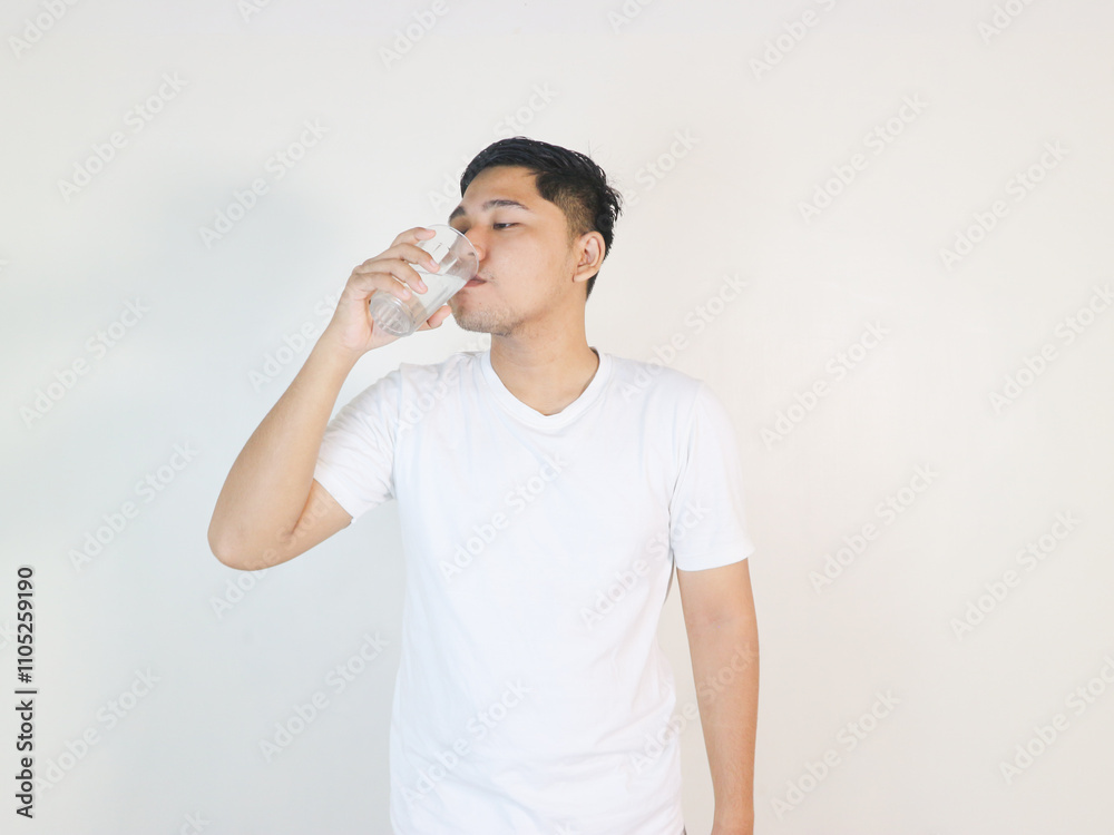 happy young asian man drinking water from glass over white background happy young asian man drinking water from glass over white background