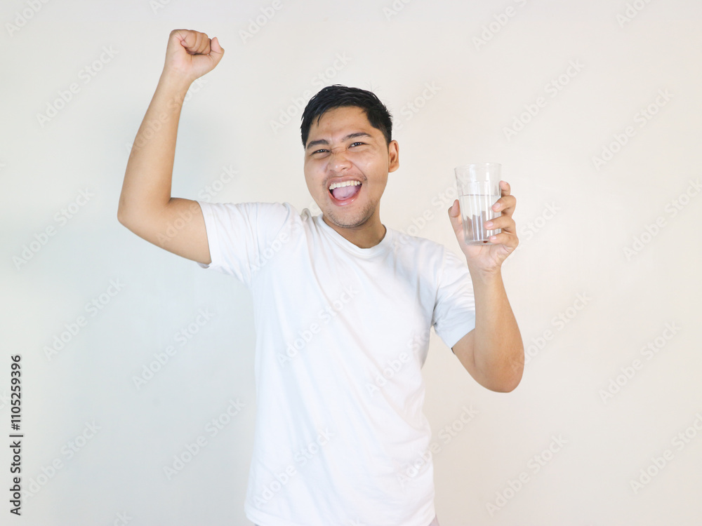 Asian sporty handsome and cheerful young man with a glass of drinking water, isolated on background Asian sporty handsome and cheerful young man with a glass of drinking water, isolated on background