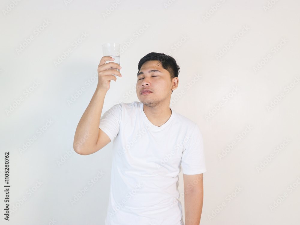 lethargic asian man holding a glass of water with closed eyes lethargic asian man holding a glass of water with closed eyes