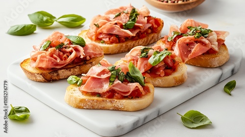 Delicious bruschetta topped with prosciutto and fresh basil on a marble platter.