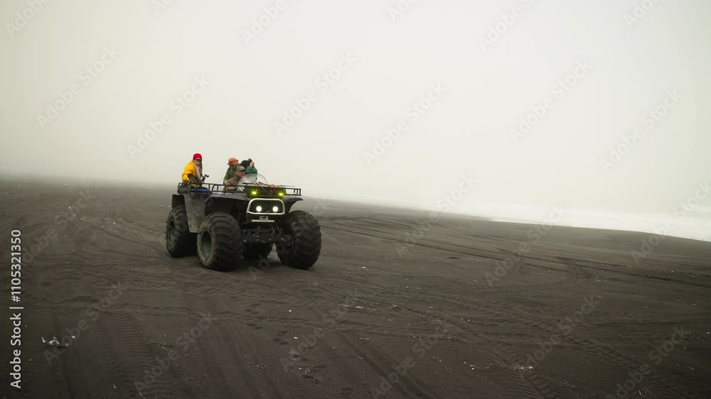 Touristic Trip In Amazing Nordic Landscape, Travelers Riding Mud Quad Over Black Sand In Island Touristic Trip In Amazing Nordic Landscape, Travelers Riding Mud Quad Over Black Sand In Island
