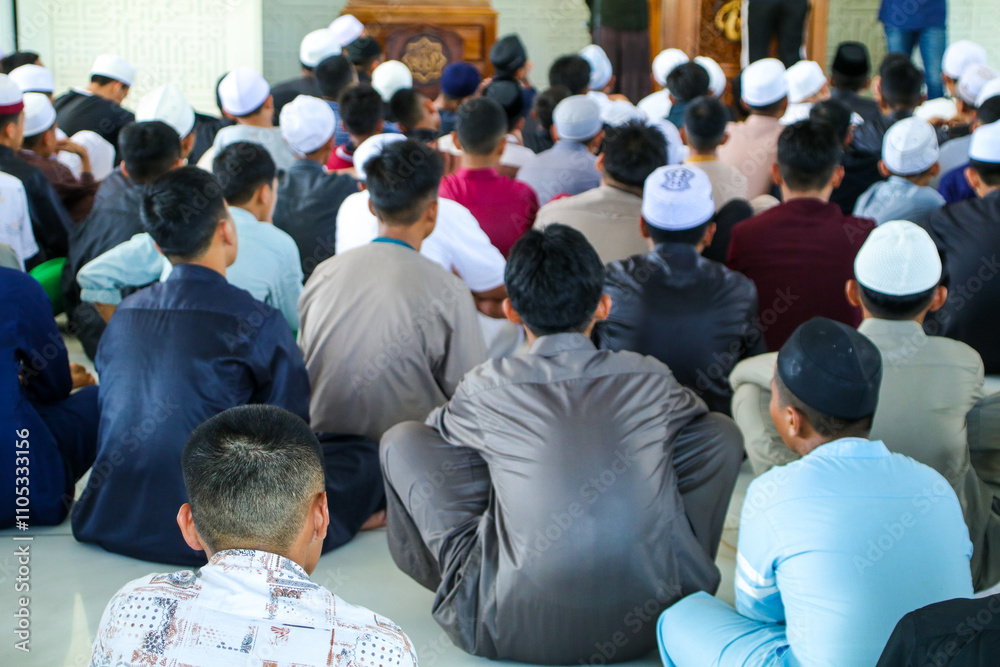 A group of students at the mosque are listening to a study wearing colorful clothes A group of students at the mosque are listening to a study wearing colorful clothes