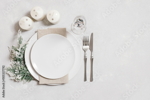 Christmas serving with empty white plate, candles and silverware on white background. Beautiful New Year table setting with copy space. Top view, flat lay.