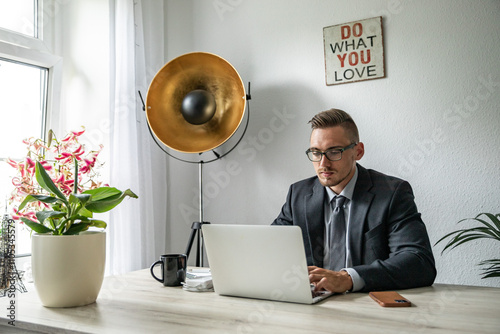 Junger Mann im Homeoffice Arbeiten am Schreibtisch Laptop konzentriert produktiv im modernen Homeoffice Umfeld photo