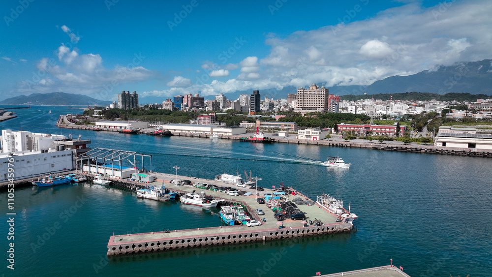Fototapeta premium Coastal view of Hualien harbor showcasing boats and city skyline under a bright blue sky