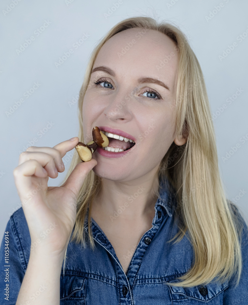 Prevention of thyroid disease. Woman holding a brazil nut in the shape of a thyroid gland. Nut rich in selenium Prevention of thyroid disease. Woman holding a brazil nut in the shape of a thyroid gland. Nut rich in selenium
