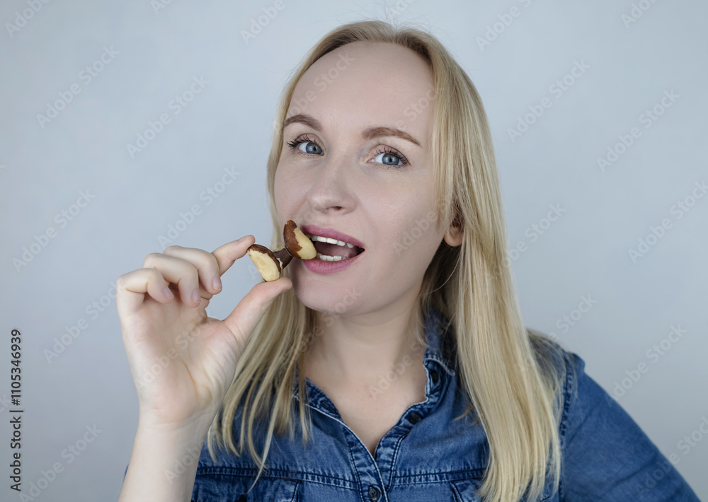 Prevention of thyroid disease. Woman holding a brazil nut in the shape of a thyroid gland. Nut rich in selenium Prevention of thyroid disease. Woman holding a brazil nut in the shape of a thyroid gland. Nut rich in selenium