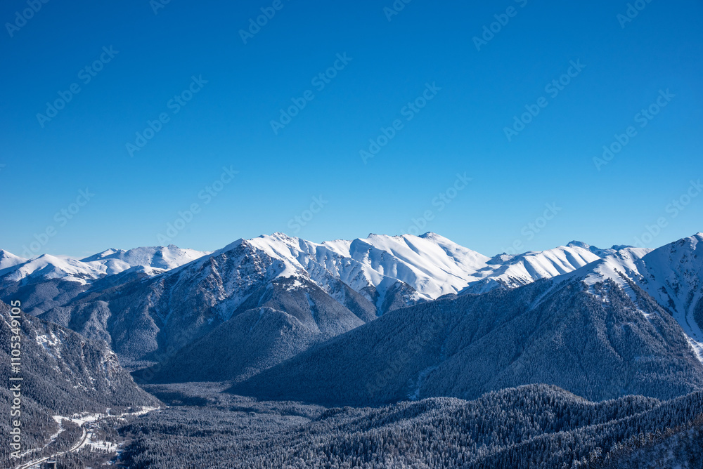 Fototapeta premium Beautiful landscape of the Arkhyz ski resort with mountains, snow, forest on sunny winter day. Caucasus Mountains, Russia.