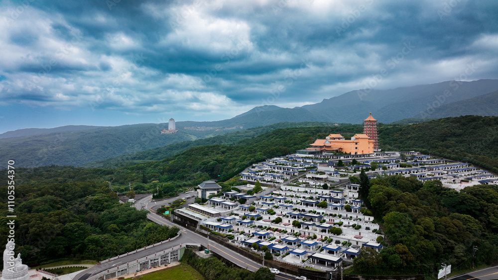 Fototapeta premium Aerial view of a serene cemetery in Taiwan surrounded by lush hills and historic buildings