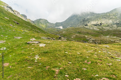 High mountain scenery with highest part of valley covered by meadows with rocky mountain peaks above in Graian Alps in Italy photo