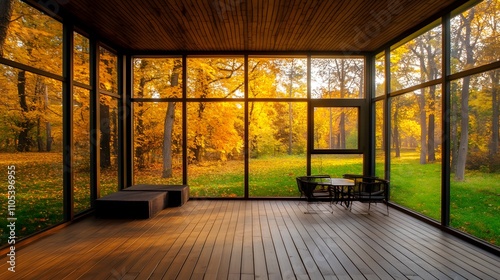 A sunroom with large windows, a wooden floor, and a table in the center of it overlooking a green lawn and trees