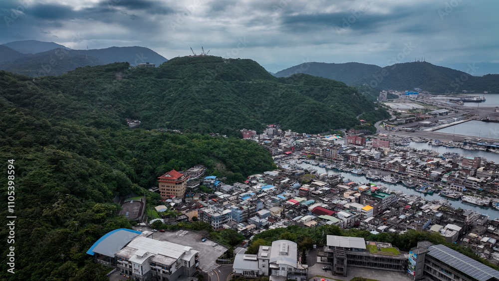 Obraz premium Aerial view of Nanfangao harbor in Taiwan with mountains and buildings on a cloudy day
