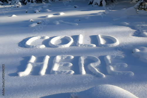 COLD HERE written in fresh snow with footprints scattered across the ground