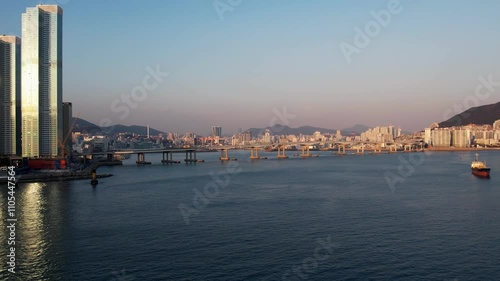 Aerial Drone Footage Showcases The Stunning Namhang Bridge At Songdo Beach, Busan, South Korea. The Shot Captures The Vibrant Sunset Illuminating The City Skyline, Evoking A Serene Mood. photo