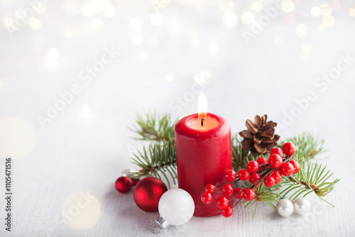 Advent candle with  Christmas decoration and lights of garland   on white  rustic wooden  table.  Selective focus.  Focus on candle flame.