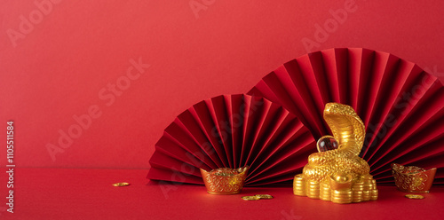 A vibrant red and gold themed setup showcasing traditional Chinese new year decorations, including a gold snake statue symbolizing the year 2025, complemented by red paper fans photo