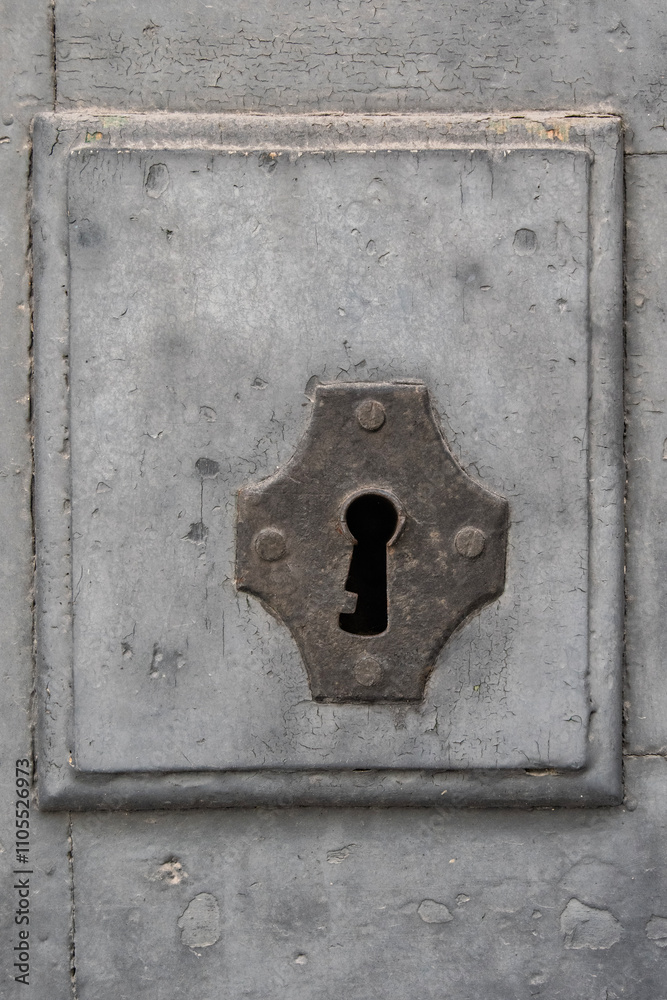 keyhole in an old door painted grey and seen from up close