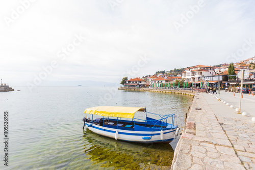 Traditional boat in the waters of Lake Ohrid with colorful houses lining the shore.