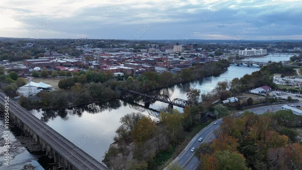Drone shot of intersection with cars and river with bridge and dam in autumn. American small town in background. Aerial wide shot. Drone shot of intersection with cars and river with bridge and dam in autumn. American small town in background. Aerial wide shot.
