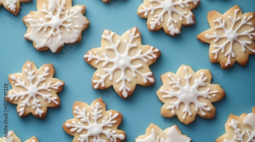 Overhead view of snowflake sugar cookies on light teal background. Delicious holiday treats decorated with white icing, sugar. Perfect for festive celebrations. Handcrafted with intricate details.