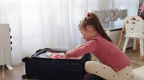 Little girl getting ready for travel and packing clothes in suitcase. Holidays, voyage and traveler concept