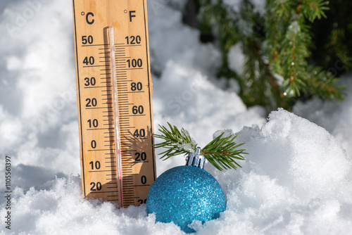 Christmas toy ball near tree and thermometer on natural snow in winter forest. Weather forecast for New Year and Christmas holidays. Frosty sunny day for happy free time in nature outdoor