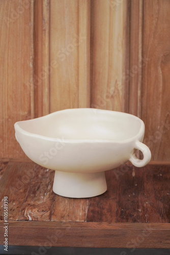 A minimalist white ceramic bowl stands on a rustic wooden surface. This stylish and functional bowl is perfect for serving salads, fruits, or snacks.