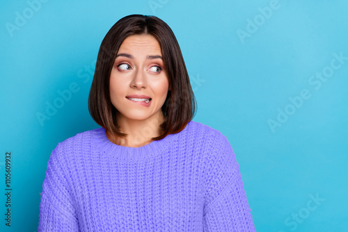 Portrait of attractive puzzled brown-haired girl biting lip thinking copy space isolated over bright blue color background