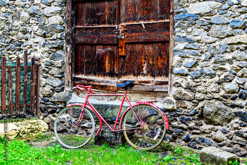 Red vintage bicycle next to a rustic stone house in the village of Viella, in the Aran Valley, Catalonia, Spain