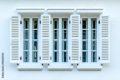 A row of beautifully symmetrical closed white shuttered windows set in a white wall, depicting a classic and serene architectural style and rhythm in design. photo