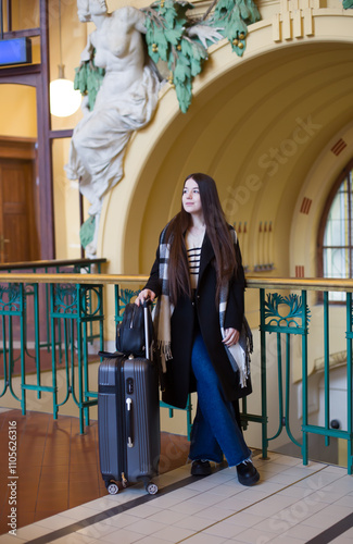 Stylish Female Traveler Standing at Train Station with Luggage