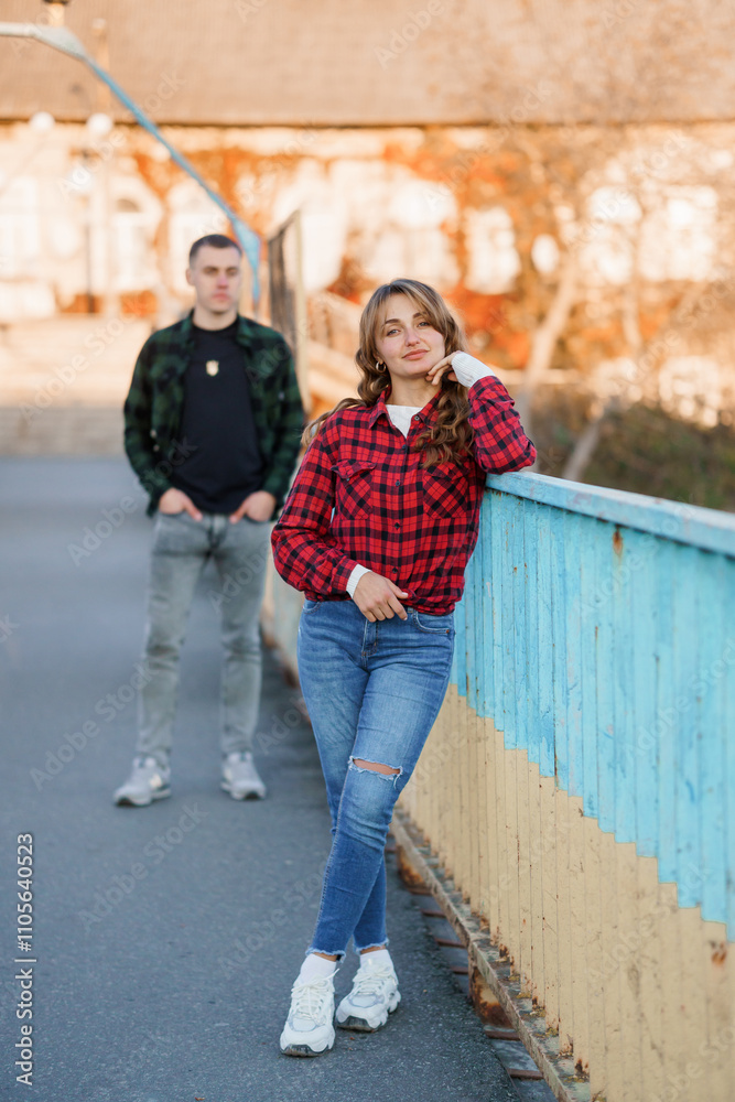 Young couple enjoying a sunny day while posing casually on a colorful bridge Young couple enjoying a sunny day while posing casually on a colorful bridge