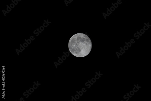 Obraz na płótnie A close-up shot of the full moon captured through a telephoto lens, revealing its surface with visible craters, showcasing the moon's detailed and captivating features w salonie