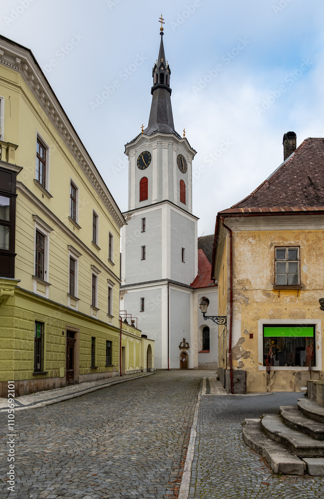 A striking view of a church with a tall tower in the town of Kraliky, showcasing its historic architecture and serene presence against the backdrop of a quaint urban setting