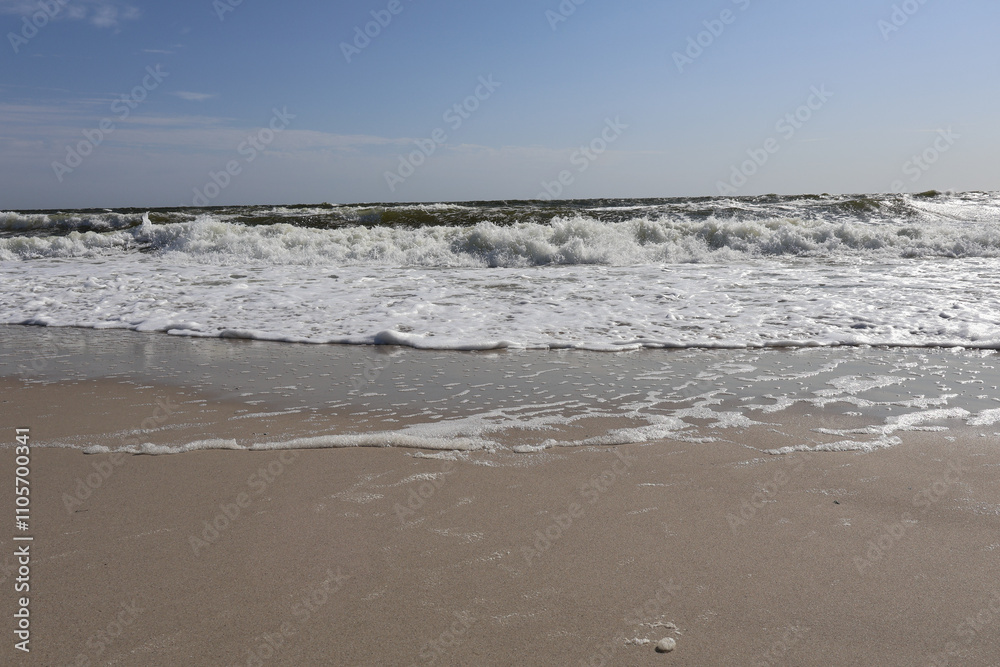 A peaceful view of ocean waves gently washing onto a sandy beach under a bright blue sky, capturing the beauty of nature and the tranquility of the seaside A peaceful view of ocean waves gently washing onto a sandy beach under a bright blue sky, capturing the beauty of nature and the tranquility of the seaside