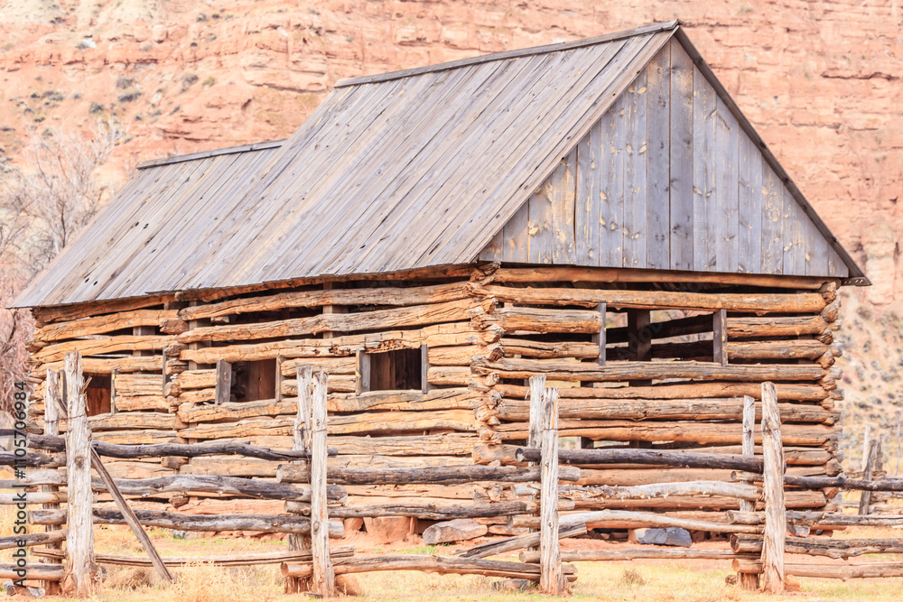 Naklejka premium A rustic log cabin with a wooden fence in front of it