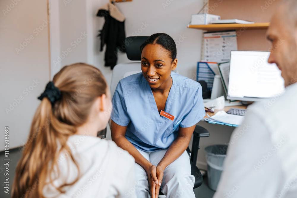 Smiling young doctor talking with girl patient in medical examination room at clinic Smiling young doctor talking with girl patient in medical examination room at clinic