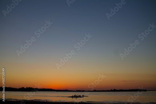 Minimalist sunset over a tranquil river. The expansive sky, with its gradient of golden and soft blue hues, creates an abstract composition. The horizon sits subtly at the bottom.
