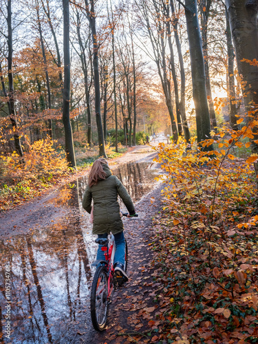 girl on bicycle on very wet forest path in dutch autumn near utrecht