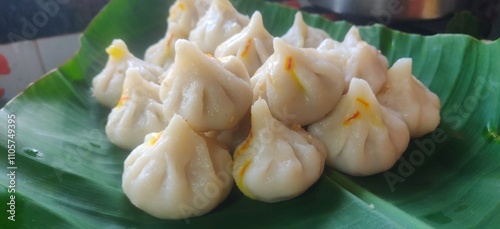 Maharashtrian sweet of Modak that is offered to Lord Ganesh, garnished with kesar (saffron) to be had with Ghee bowl and Lord Ganpati in the background. photo