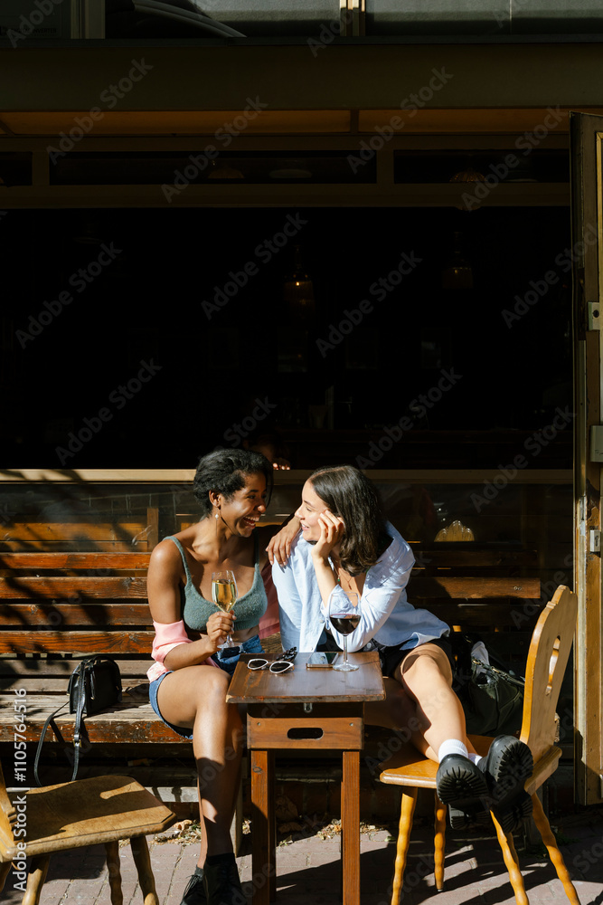 Female friends talking with each other while sitting at restaurant Female friends talking with each other while sitting at restaurant