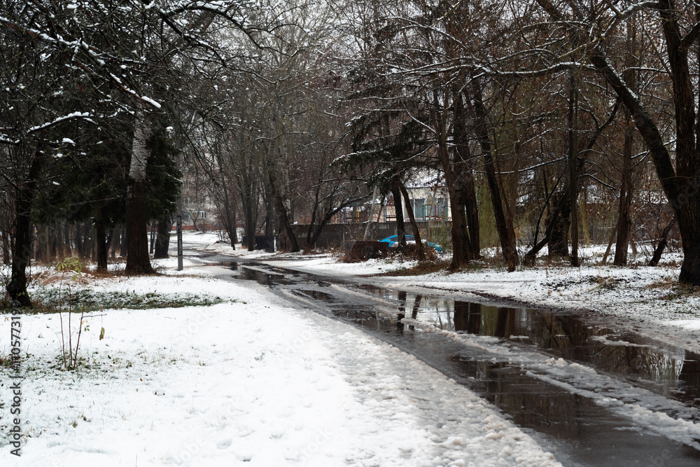 Tranquil city park in winter featuring a winding walkway lined with trees. Tranquil city park in winter featuring a winding walkway lined with trees.