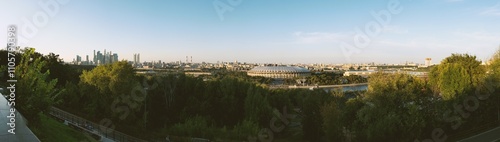 Panoramic view of Moscow’s cityscape during evening hours, featuring Luzhniki Stadium, Moscow City skyscrapers, and the tranquil greenery surrounding the area photo