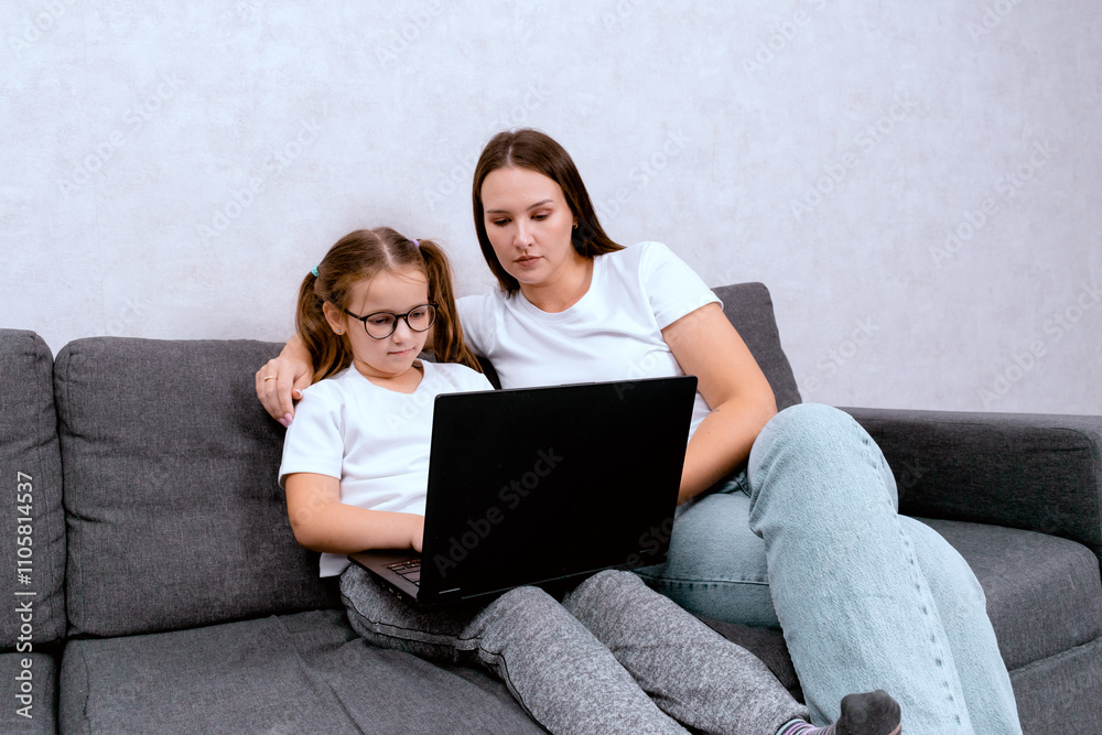 A mother working from home with her daughter, both shopping online using a laptop. The woman hugs her child, creating a cozy and productive home office atmosphere in the living room. A mother working from home with her daughter, both shopping online using a laptop. The woman hugs her child, creating a cozy and productive home office atmosphere in the living room.